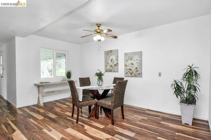 Dining area with a ceiling fan and dark wood-style floors