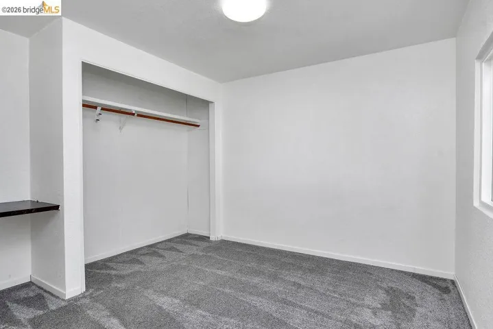 Unfurnished bedroom featuring dark colored carpet and a closet