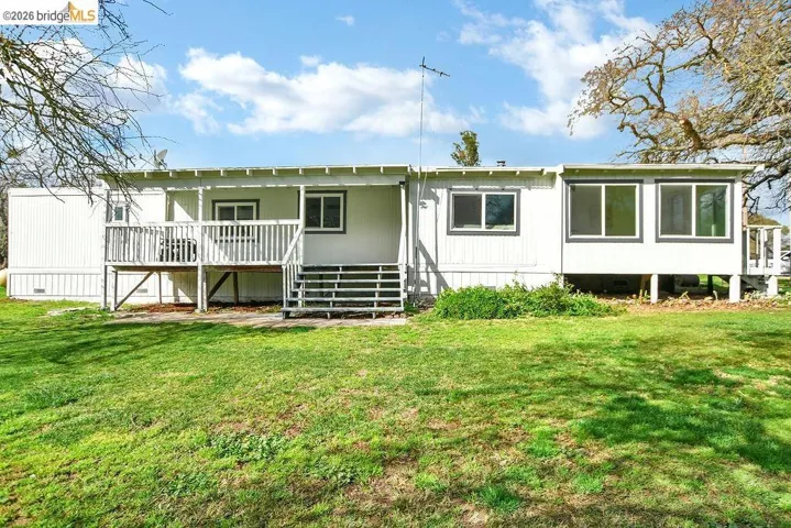 Rear view of house featuring a yard and covered porch