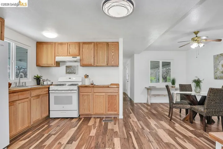 Kitchen featuring white appliances, dark wood finished floors, and ceiling fan