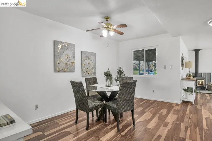 Dining room featuring dark wood-style flooring, ceiling fan, and a wood stove