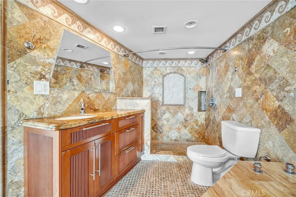 legant vanity area featuring custom cabinetry and intricate ceramic tilework on both walls and floors, creating a standout bathroom.