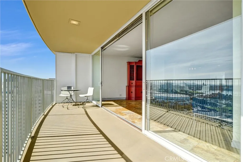 Floor-to-ceiling glass doors stretch across the living area, opening completely to the balcony for effortless entertaining and stunning views.