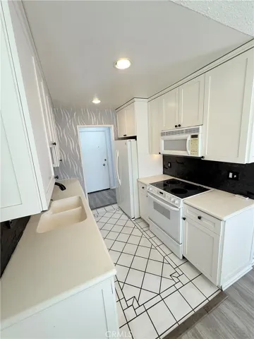 Galley kitchen with tile floors and stone backsplash