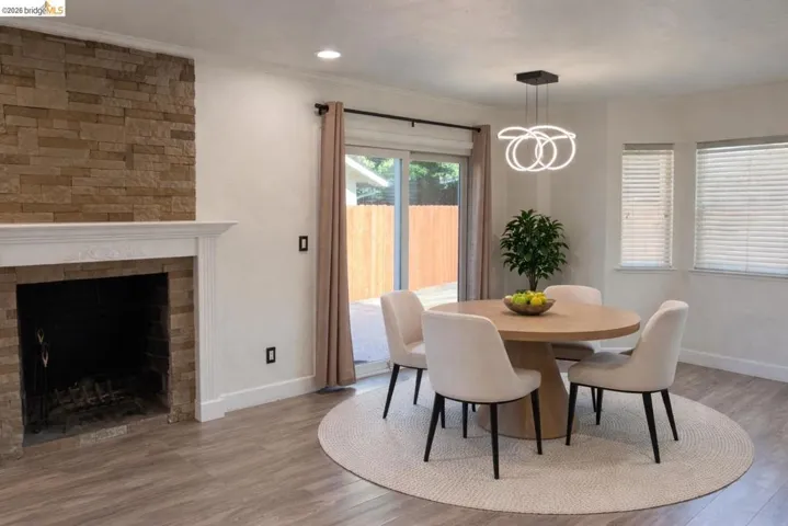 Dining space featuring light wood-type flooring, crown molding, a fireplace, and recessed lighting