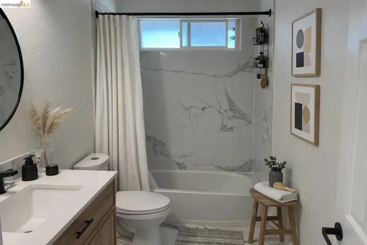 Full bathroom featuring vanity, shower / bath combo, and a textured wall
