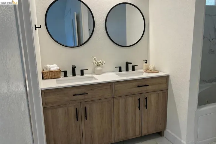 Full bath featuring double vanity, a textured wall, a whirlpool tub, and a shower