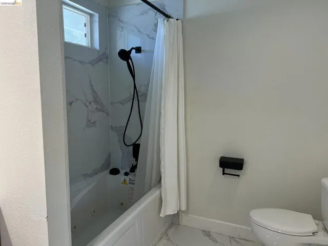 Bathroom with a combined bath / shower with jetted tub and light marble finish floors