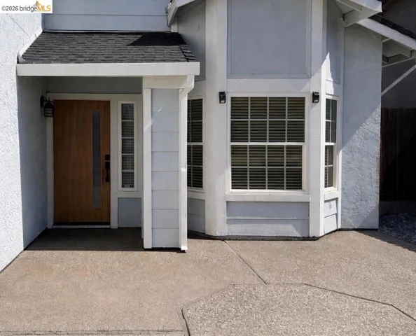 View of exterior entry with a shingled roof and stucco siding