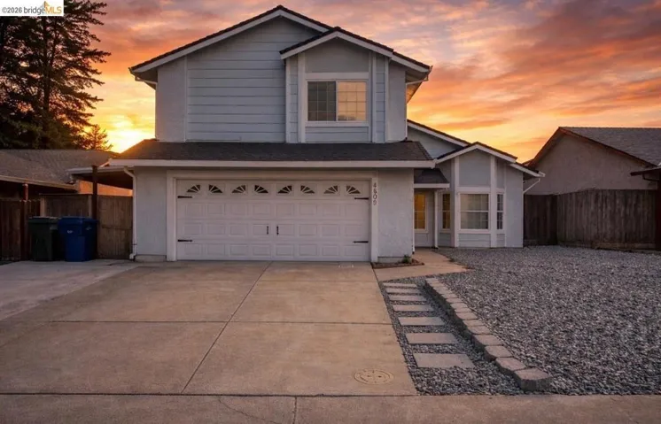 Traditional-style home featuring an attached garage, concrete driveway, and a shingled roof