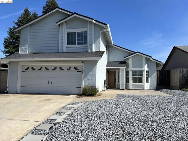 Traditional-style home with roof with shingles, a garage, and concrete driveway