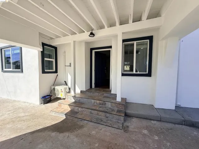 View of exterior entry featuring stucco siding and a patio area
