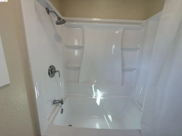 Bathroom featuring a textured wall and shower / bath combo