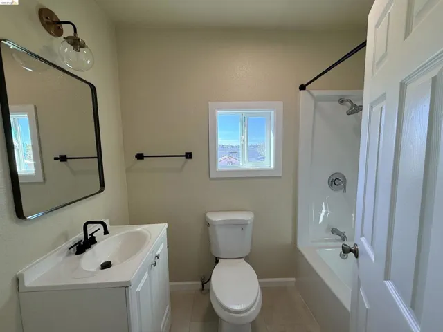 Bathroom with vanity, bathing tub / shower combination, and light tile patterned flooring
