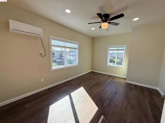Spare room featuring a ceiling fan, dark wood-style floors, healthy amount of natural light, and recessed lighting