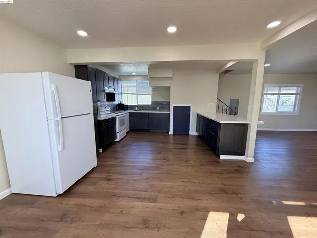 Kitchen with white appliances, light countertops, dark wood-type flooring, recessed lighting, and a textured ceiling