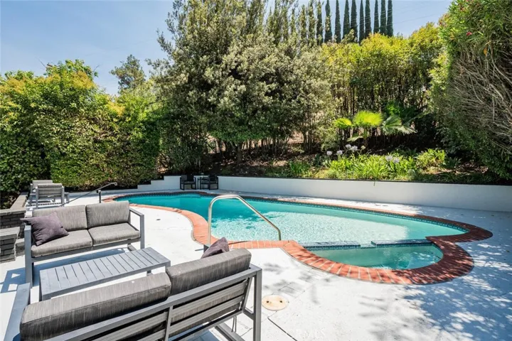 Poolside entertaining area with lounge seating and tranquil backyard setting.