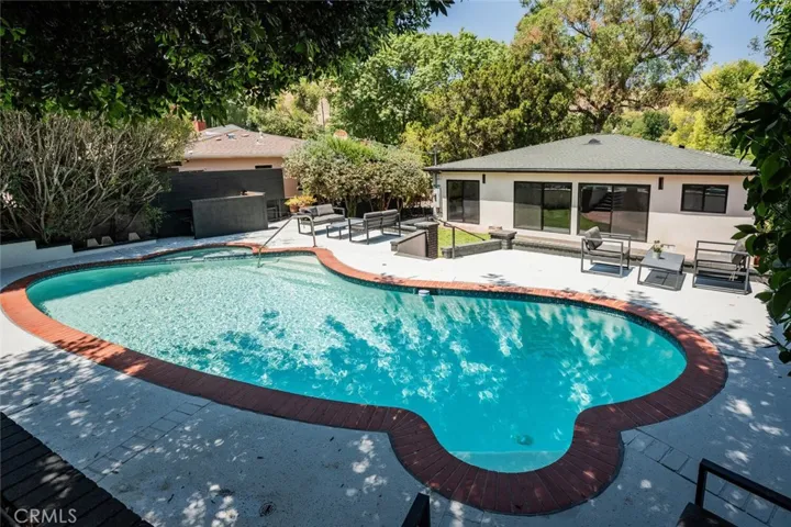 Resort-style pool and patio surrounded by mature landscaping.