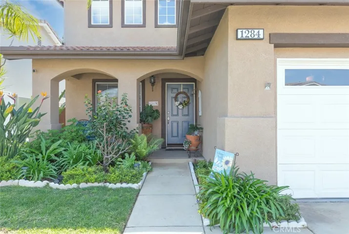 
The entryway is welcoming with its manicured lawn, flowering plants, and a path leading to a warm, inviting front door.