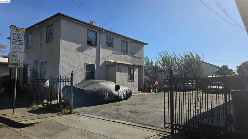 Side of property featuring a fenced front yard, a gate, and stucco siding