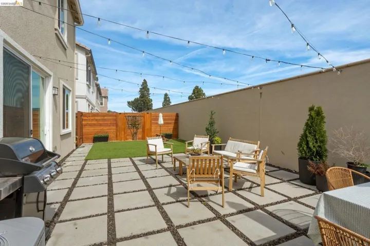 Fenced backyard featuring an outdoor hangout area, a patio area, and a grill