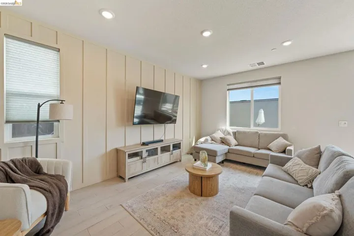 Living room featuring a decorative wall, light wood-style flooring, and recessed lighting