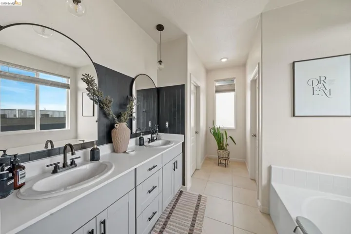 Full bathroom featuring double vanity, a garden tub, and light tile patterned floors