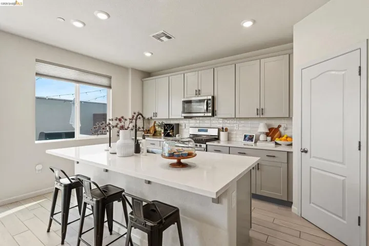 Kitchen featuring a breakfast bar area, wood tiled floors, stainless steel appliances, recessed lighting, and a kitchen island with sink