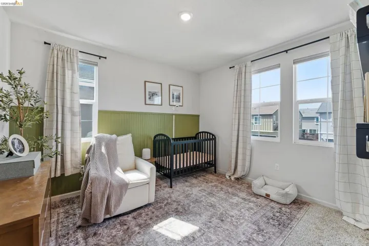 Bedroom with a nursery area, wainscoting, and carpet floors