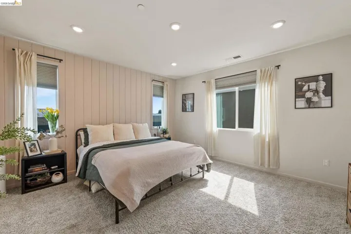 Bedroom featuring light carpet, recessed lighting, and wooden walls