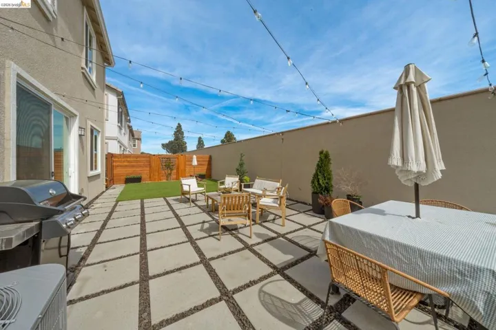 Fenced backyard with a patio area, an outdoor hangout area, and a grill