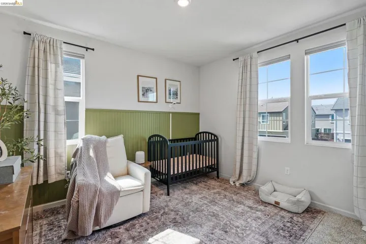 Bedroom featuring a crib and a wainscoted wall
