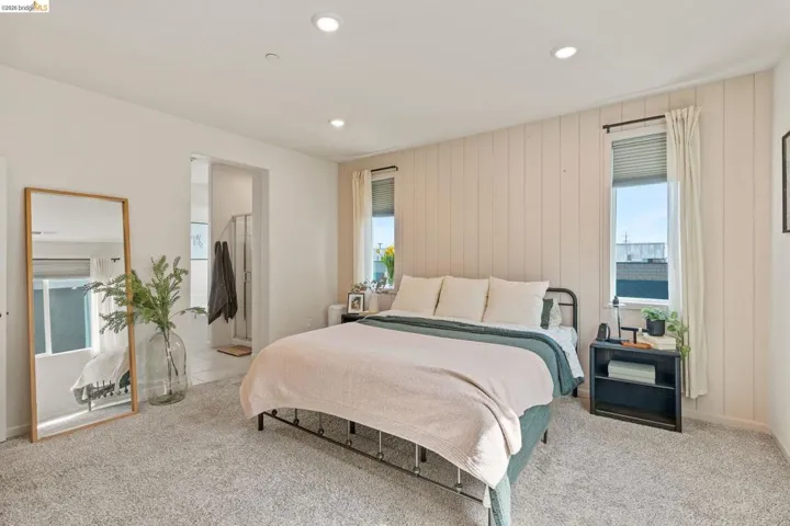 Bedroom with connected bathroom, recessed lighting, light carpet, and wood walls