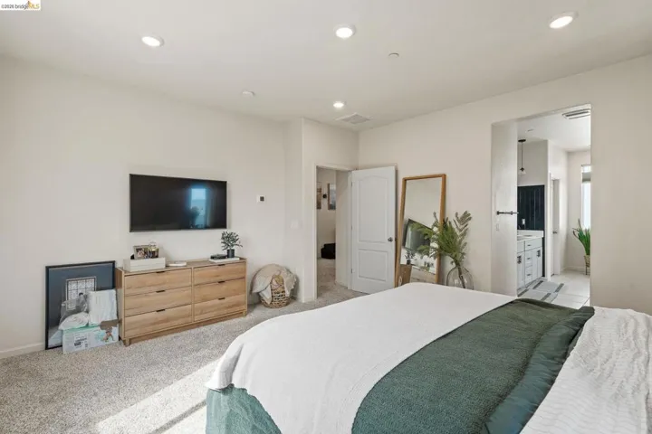 Bedroom with light carpet, recessed lighting, and connected bathroom