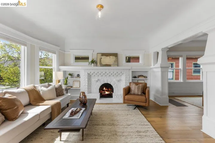 Living area with built in features, light wood finished floors, and a lit fireplace