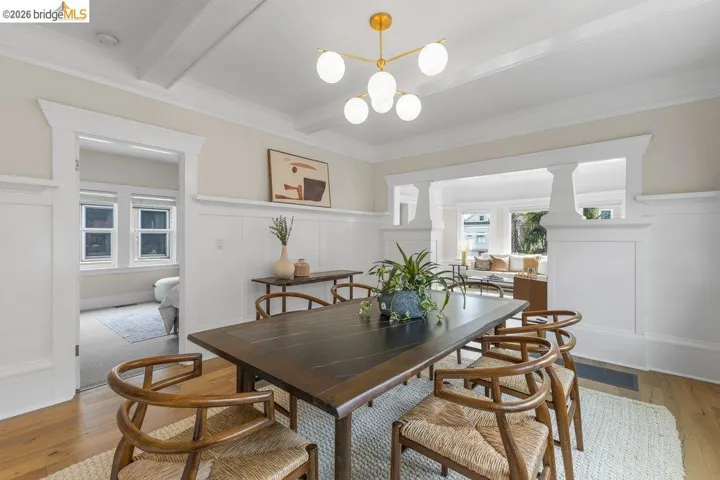 Dining area featuring a decorative wall, hardwood / wood-style flooring, a wainscoted wall, ornamental molding, and hanging lights