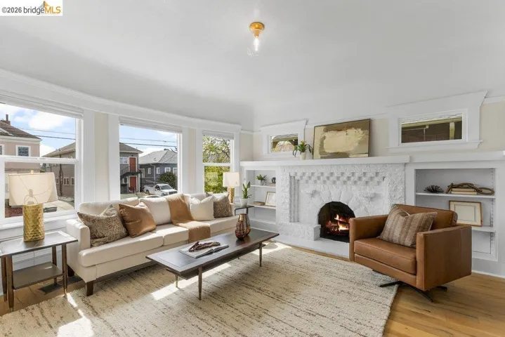 Living room featuring built in features, light wood finished floors, and a warm lit fireplace