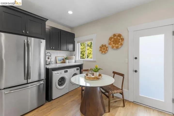 Kitchen featuring freestanding refrigerator, backsplash, dark cabinets, and light wood-style flooring