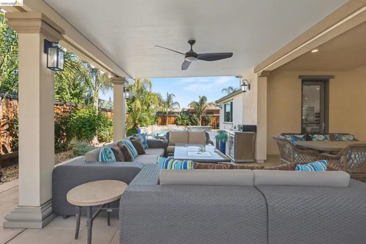 Fenced backyard featuring an outdoor living space, a patio area, and a ceiling fan