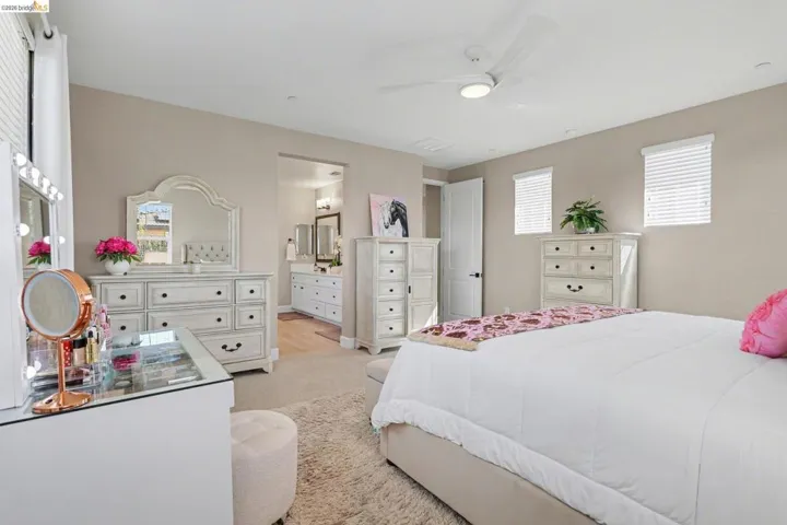 Bedroom with light colored carpet, ceiling fan, and ensuite bathroom