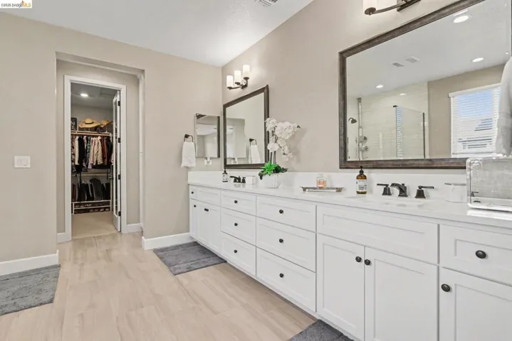 Full bath with double vanity, a stall shower, recessed lighting, and a spacious closet