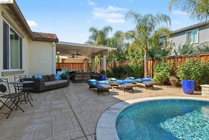 View of pool with outdoor furniture, patio surround, and a fenced backyard