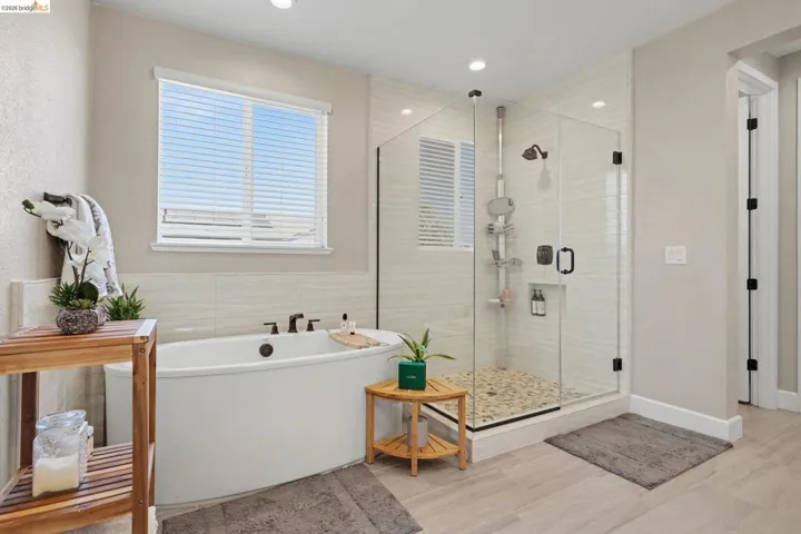 Full bath featuring a freestanding tub, a stall shower, and light wood finished floors