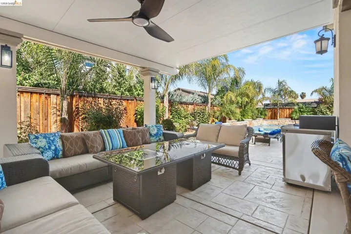 Fenced backyard with an outdoor living space, ceiling fan, and a patio