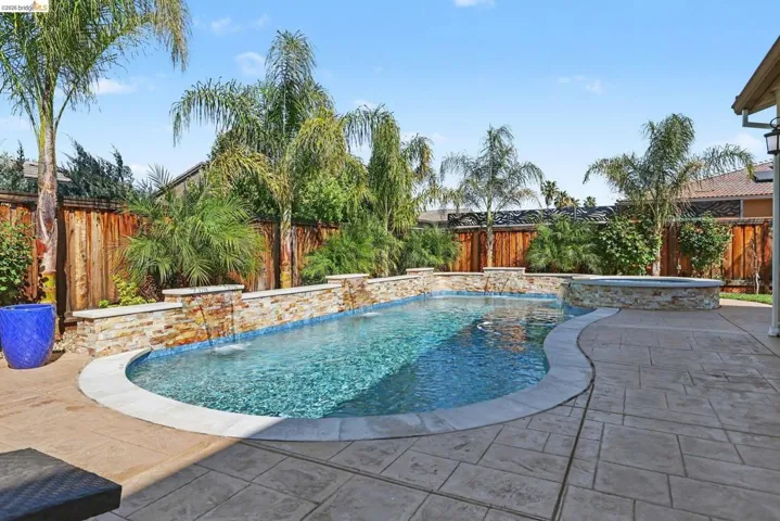 Combined pool / hot tub featuring a fenced backyard and a patio area