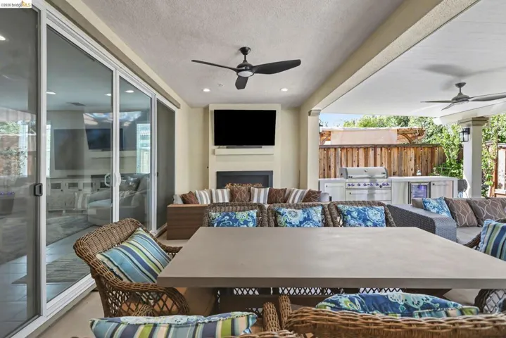 View of patio featuring a ceiling fan, an outdoor living / dining area, area for grilling, and wine cooler