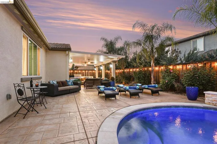 Pool at dusk with an outdoor hangout area, a fenced backyard, and a patio area