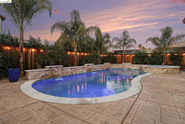 Combined pool / hot tub featuring a fenced backyard and a patio