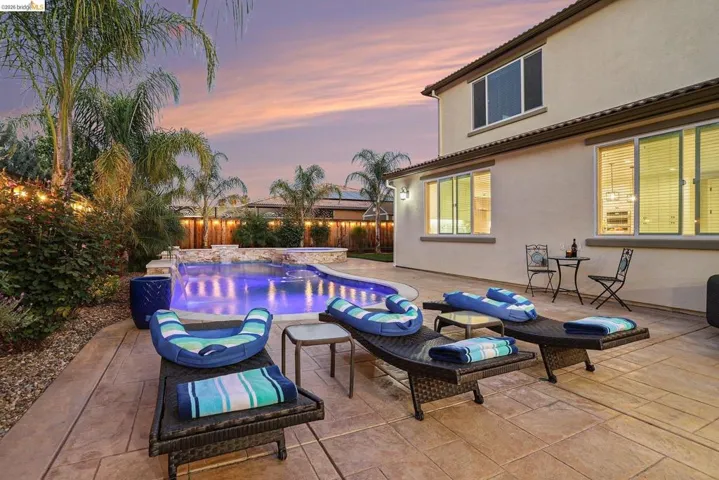 Pool at dusk with a fenced backyard, a patio, a pool with connected hot tub, and an outdoor living space
