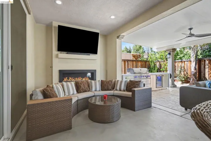 View of patio featuring an outdoor living space with a fireplace, ceiling fan, and grilling area